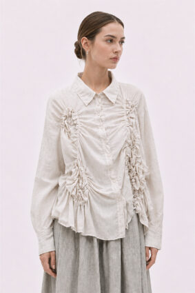 The La Vaca Loca Somatico Shirt Cold White CW is a long-sleeved shirt with a collar and textured, irregular gathers on the front, made of soft voile fabric.