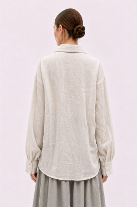 The La Vaca Loca Somatico Shirt Cold White CW is a long-sleeved shirt with a collar and textured, irregular gathers on the front, made of soft voile fabric.