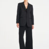 Model wearing Mela Purdie Suit Pant in Black with a matching black tailored blazer.