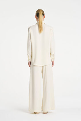 Model wearing Mela Purdie Suit Pant in Vanilla and Black fine vertical stripes.