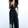 Desigual Tropical Pant Negro front view showing relaxed resort-inspired silhouette and vibrant tropical print of oversized florals and lush palm leaves