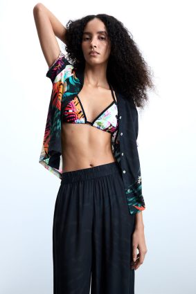 Desigual Tropical Pant Negro front view showing relaxed resort-inspired silhouette and vibrant tropical print of oversized florals and lush palm leaves