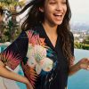Desigual Tropical Shirt Negro front view showing relaxed resort-inspired silhouette and open collar with vibrant tropical print of oversized florals and lush palm leaves
