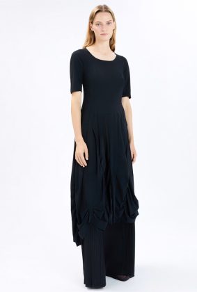 Model wearing the High Tech On Top Dress, featuring a fitted bodice, gathered seams, a wide silhouette from the waist down, and an asymmetric hem.
