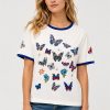 Johnny Was Contrast Binding T-Shirt Vanny in white featuring blue contrast neck and sleeve binding with embroidered butterflies and floral motifs.