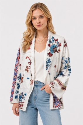 Model wearing the Johnny Was Noemi Jacket Armeria White, an ivory cotton statement jacket featuring rich floral embroidery, paisley motifs, and intricate geometric contrast detailing in cobalt, crimson, and turquoise.