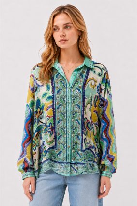 Model wearing the Johnny Was The Audrey Button Up Shirt Rosea, a fluid silk blouse featuring an intricate medley of paisley, floral, and ornamental motifs in aqua, turquoise, cobalt, lime, and golden yellow.