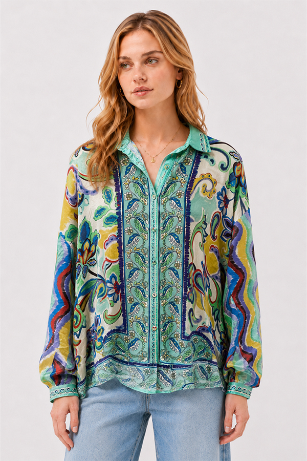 Model wearing the Johnny Was The Audrey Button Up Shirt Rosea, a fluid silk blouse featuring an intricate medley of paisley, floral, and ornamental motifs in aqua, turquoise, cobalt, lime, and golden yellow.
