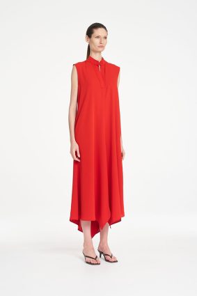 Mela Purdie Tab Soire Dress in vibrant papaya featuring a fluid silhouette, stand collar, open neckline, and asymmetric handkerchief hem