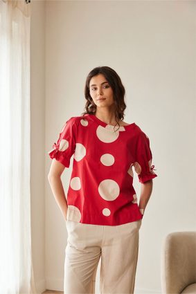 Peruzzi Polka Dot Cotton Top Red featuring a bold red and cream polka dot print with a relaxed silhouette and feminine tie detailing at the cuffs.