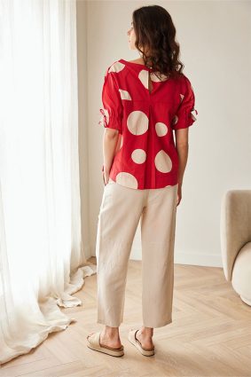 Peruzzi Polka Dot Cotton Top Red featuring a bold red and cream polka dot print with a relaxed silhouette and feminine tie detailing at the cuffs.